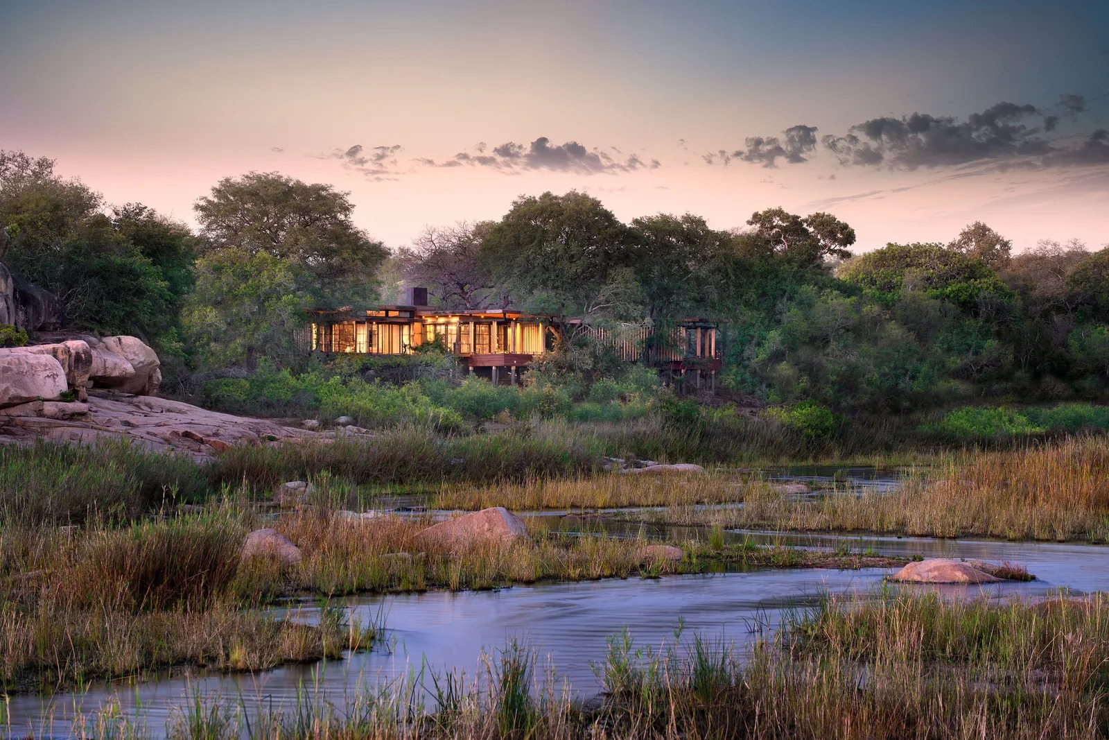 Riverside lodge glowing at dusk above the water