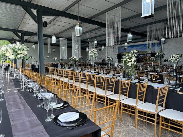 Long banquet tables set with gold chiavari chairs and white florals