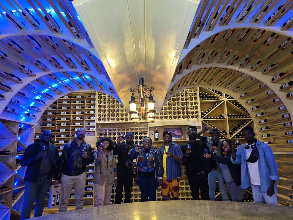 Gibby Memane raising a glass with a tour group inside a wine cellar