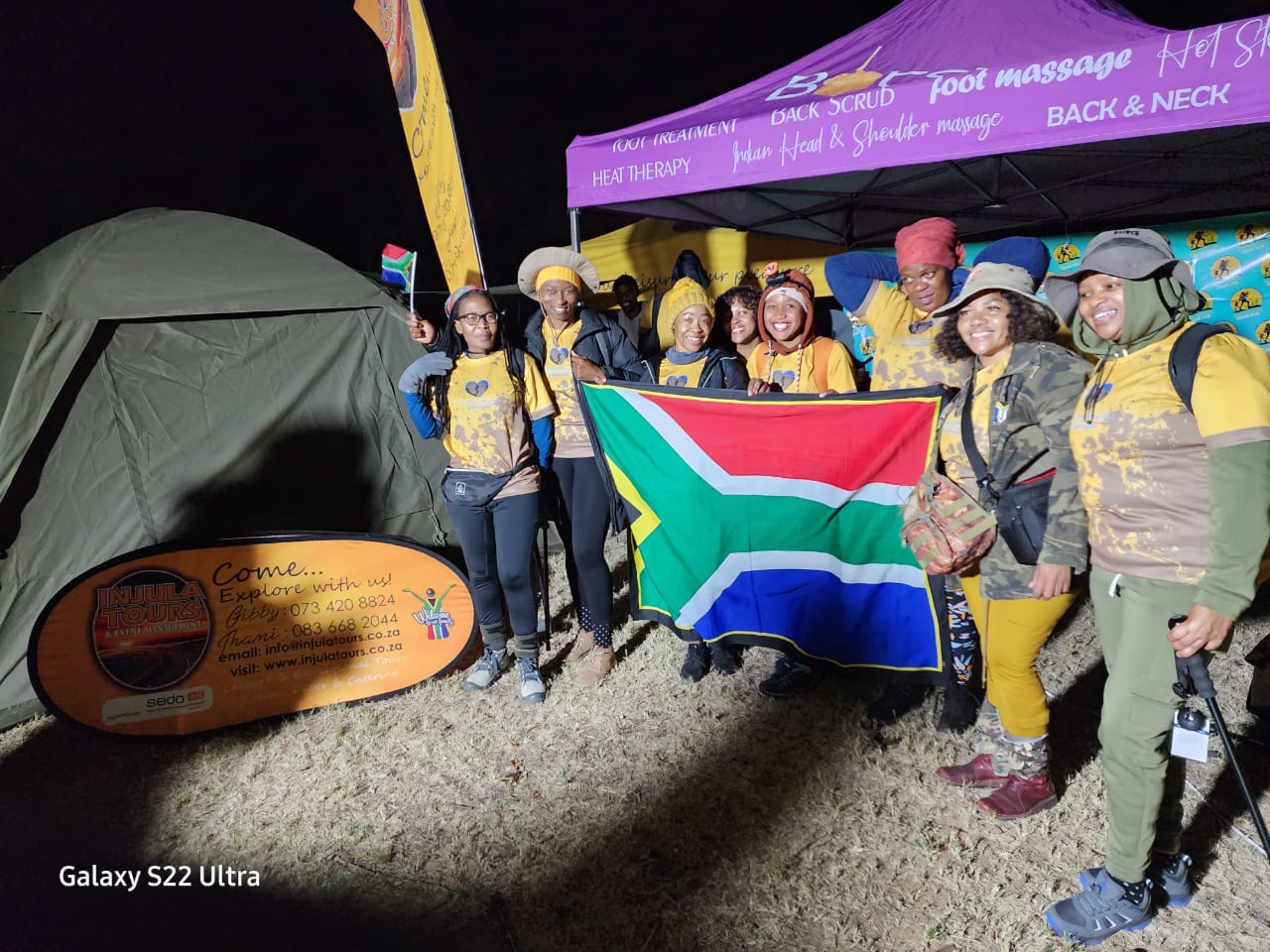 The Injula Tours team holding the South African flag at a night camp site