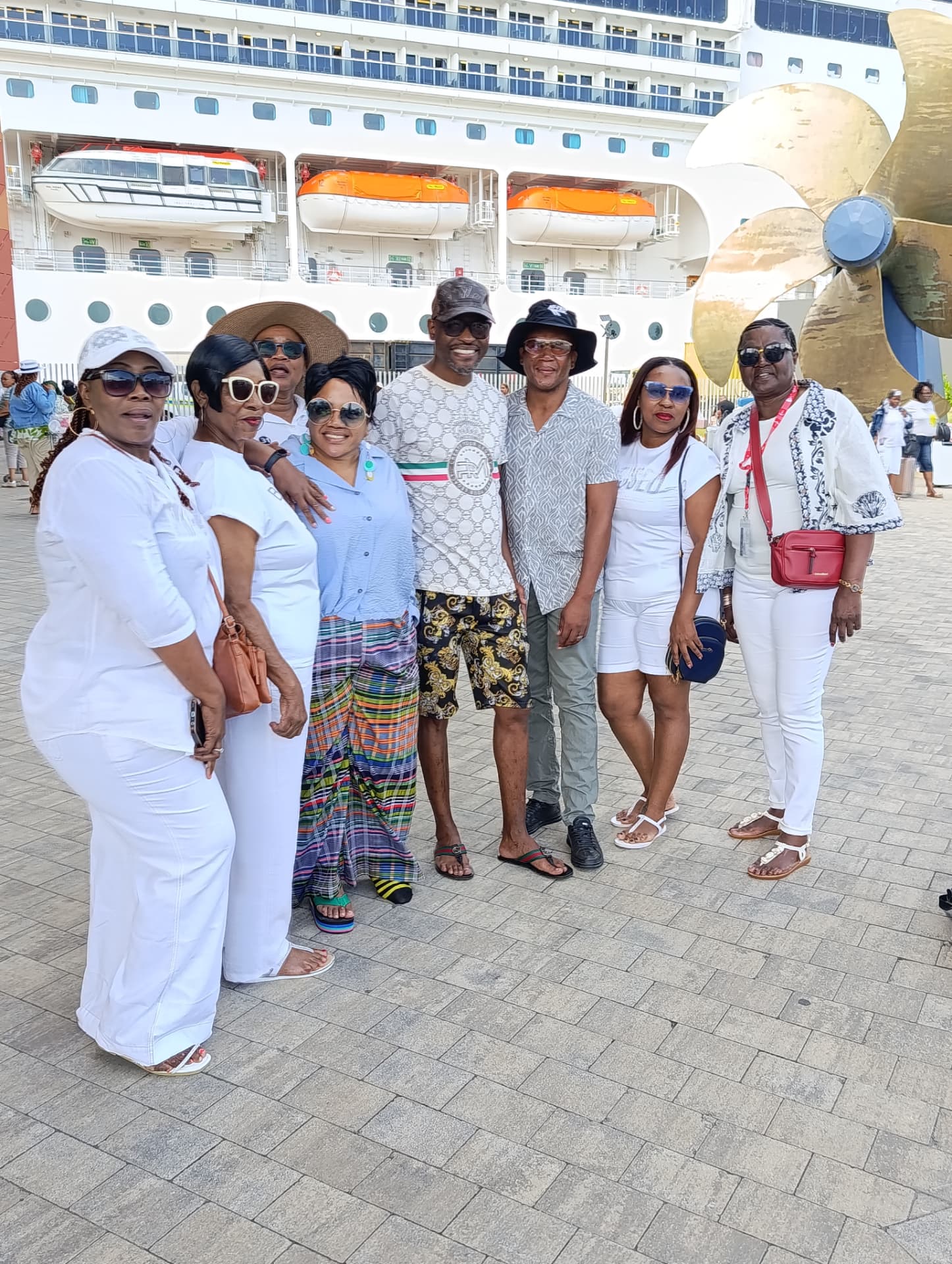 Guests in white at the cruise terminal beside the ship