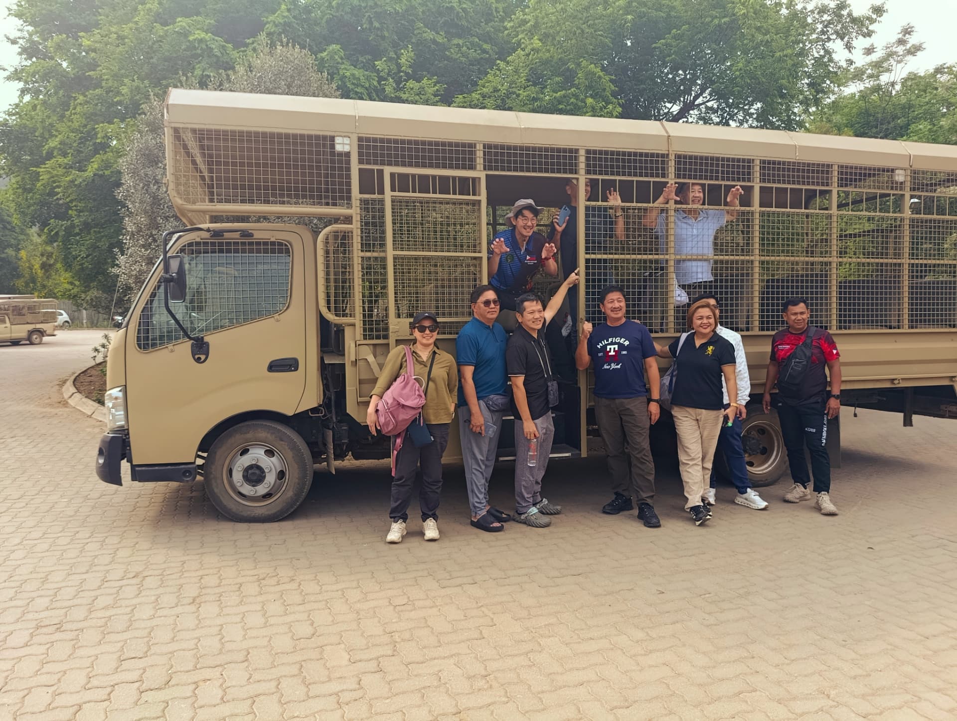 Guests posing beside the open safari truck before a game drive